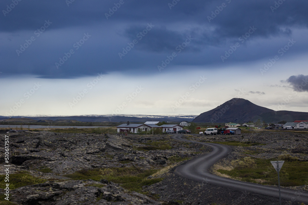 beautiful icelandic landscape with curvy road, volcano crater and mountains on the background