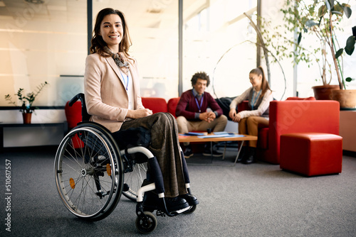 Portrait of happy businesswoman in wheelchair in office looking at camera. photo