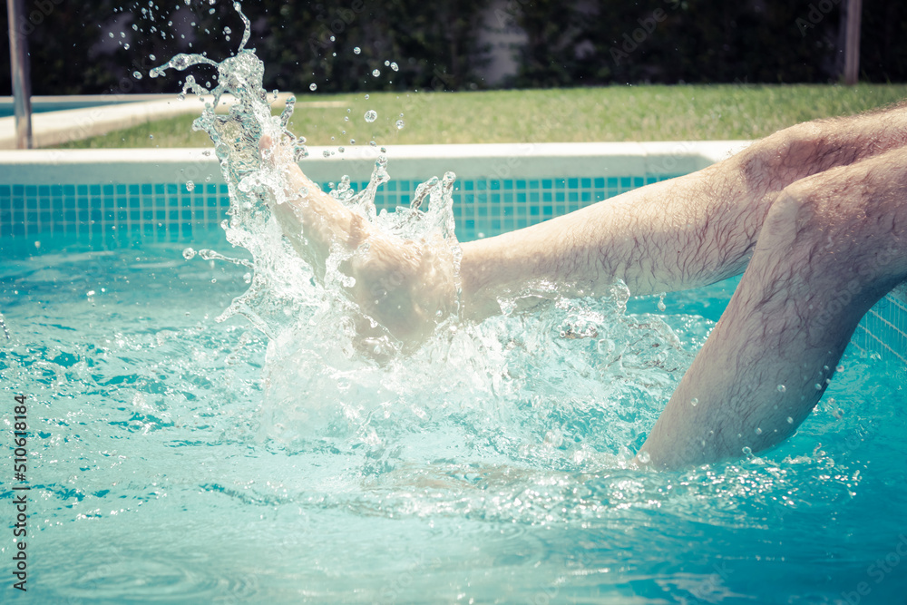 legs of man splashing in the pool on a hot summer day