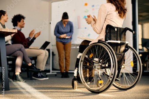 Back view of businesswoman with disability applauding during seminar in board room.