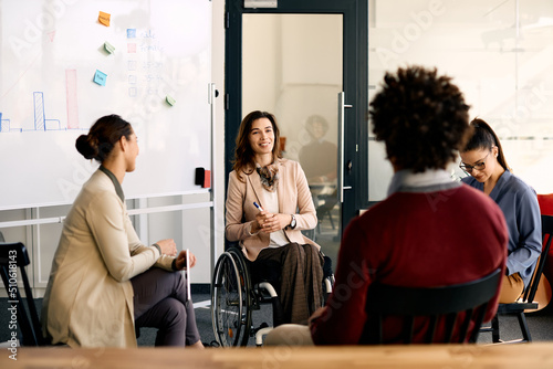 Happy disabled businesswoman brainstorming with her coworkers during presentation in meeting room. photo