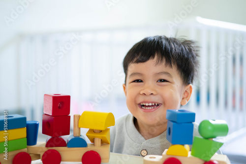 2 years old baby boy playing with wooden toy on the table