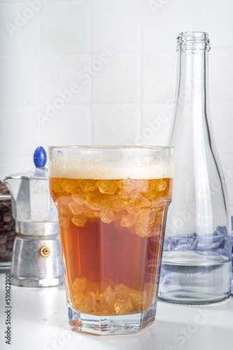 Fizzy coffee drink. Coffee espresso with carbonated mineral water and crushed ice, with coffee maker, milk roasted coffee beans on white background copy space