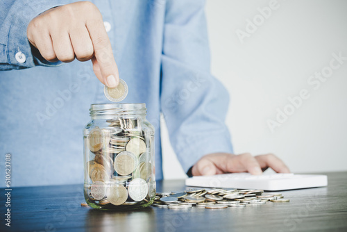 woman hand putting money into jar
