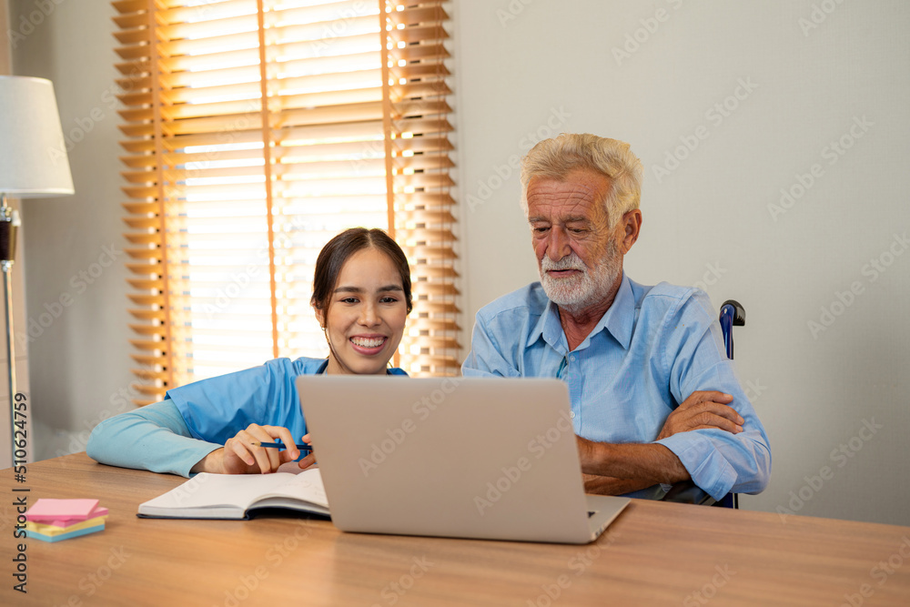 Friendly young woman nurse helping senior man in weheelchair using laptop, Elderly male patient surfing on Internet at nursing home. Friendly young woman nurse helping senior man in weheelchair using laptop, Elderly male patient surfing on Internet at nursing home.