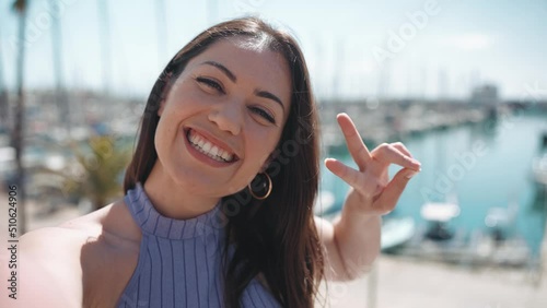 Wallpaper Mural Cheerful brunette woman showing peace gesture at the camera while standing on the embankment near the yachts outdoors  Torontodigital.ca