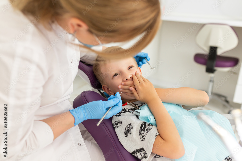 Little cute boy in the dentist's chair in the office is afraid to treat his teeth Little cute boy in the dentist's chair in the office is afraid to treat his teeth