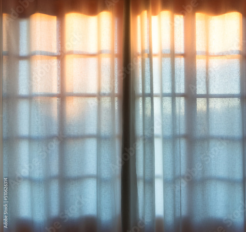 Sunset behind window with curtain.