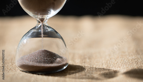 hourglass (sand clock) on the table, Hourglass as time passing concept for business deadlines, urgency, and running out of time, elapsed time concept, with copy space