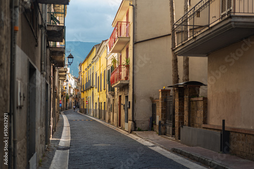 Fototapeta Naklejka Na Ścianę i Meble -  Narrow historic (medieval) streets of a small town in southern Italy. Old stone houses, wooden windows and doors, cobblestone road.