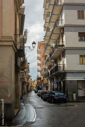 Narrow historic (medieval) streets of a small town in southern Italy. Old stone houses, wooden windows and doors, cobblestone road.