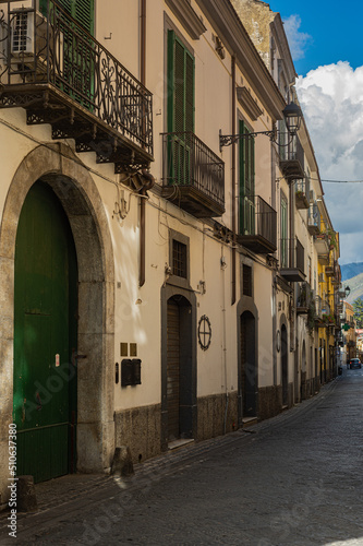 Fototapeta Naklejka Na Ścianę i Meble -  Narrow historic (medieval) streets of a small town in southern Italy. Old stone houses, wooden windows and doors, cobblestone road.