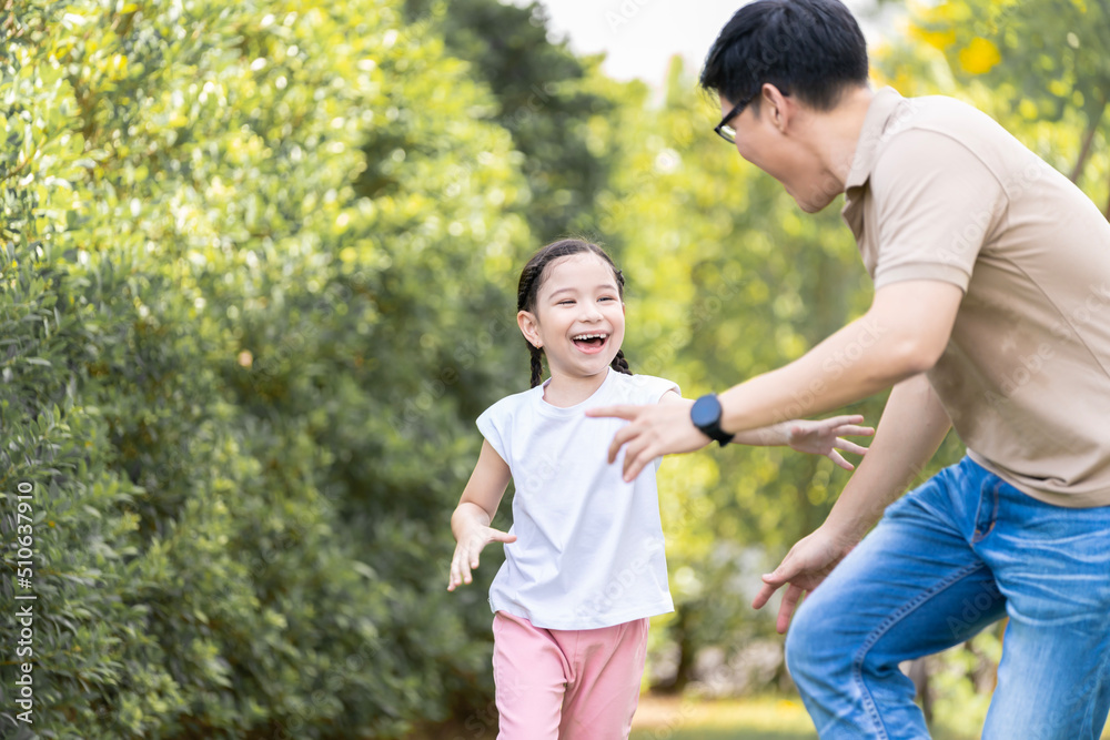 Asian girl running on the lawn in a public garden Do activities together with your family in a fun and joyful way. There is a father and mother taking care of them closely. Asian girl running on the lawn in a public garden Do activities together with your family in a fun and joyful way. There is a father and mother taking care of them closely.