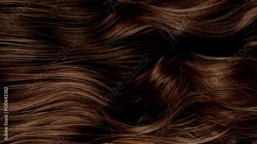 Closeup on luxurious curly brown hair with highlights.