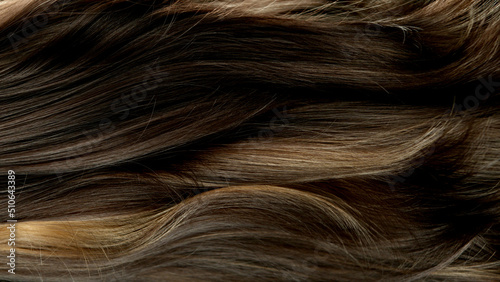 Closeup on luxurious curly brown hair with highlights.