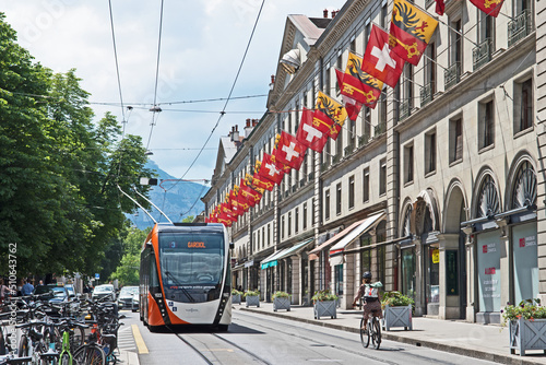 A trolly bus passes through the rue de la Corraterie whose buildings are decked with the flags of Geneva and Switzerland photo