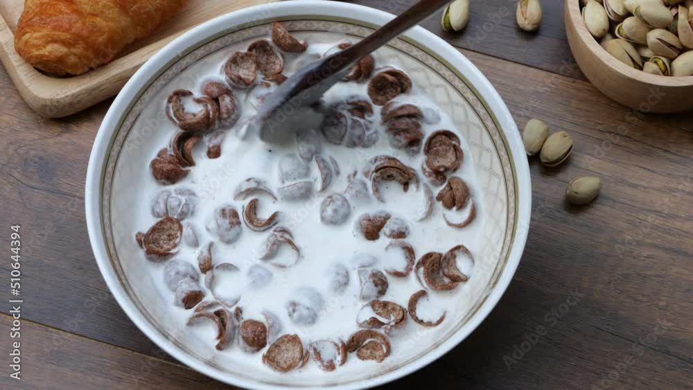 4k-Top view slow motion of hand stirring cereal with milk on wooden background, healthy breakfast concept. 4k-Top view slow motion of hand stirring cereal with milk on wooden background, healthy breakfast concept.