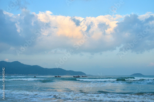 Sea and sky landscape. landscape of the sea coast with silhouettes of mountains in the distance , waves and fishing boats , sky with yellow from sunset clouds. .Travelling to the sea coast concept 
