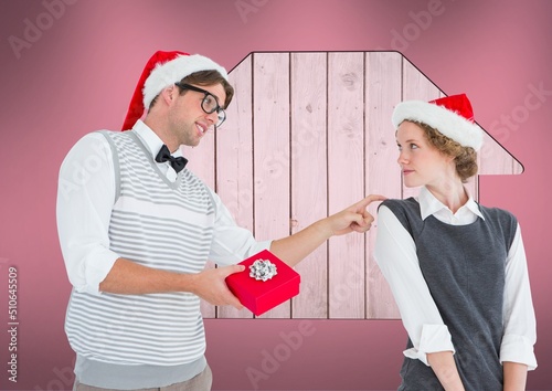 Caucasian man giving a christmas gift to his wife with house icon and copy space on pink background