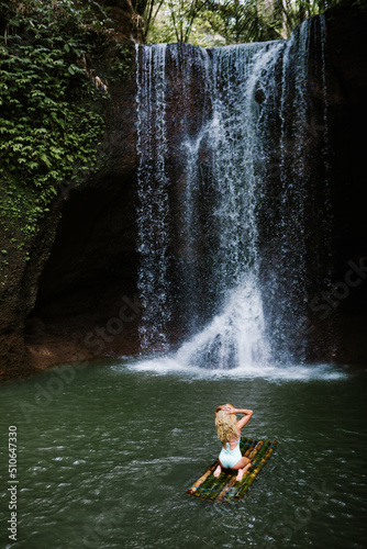 Woman have fun in natural pool under falling water of Suwat waterfall in tropical jungle. Nature day tour, swimming activity adventure and fun at family tourist camp on summer vacation in Bali island. photo