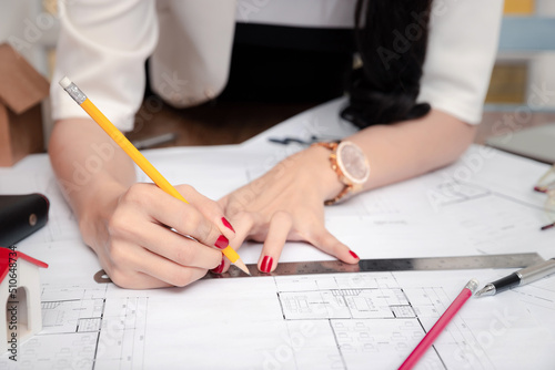 Female Architect working with pencil and ruler on blueprint. Architect engineer contractor design working drawing sketch plan blueprint and making architectural construction house building.