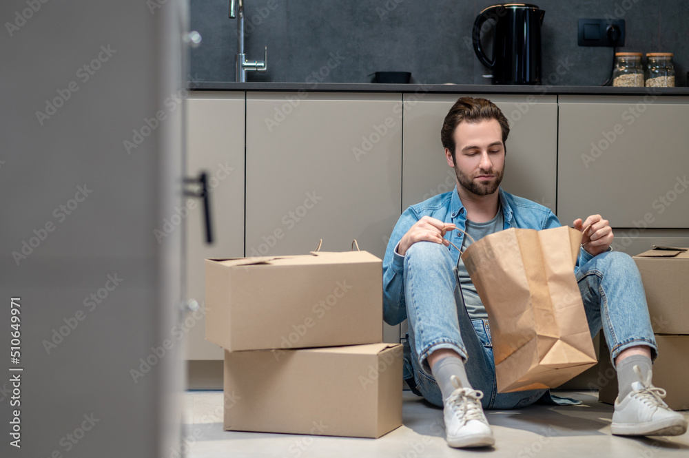 Man looking into bag sitting on floor Man looking into bag sitting on floor