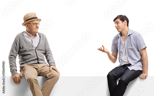 Elderly man and a guy talking and sitting on a blank panel