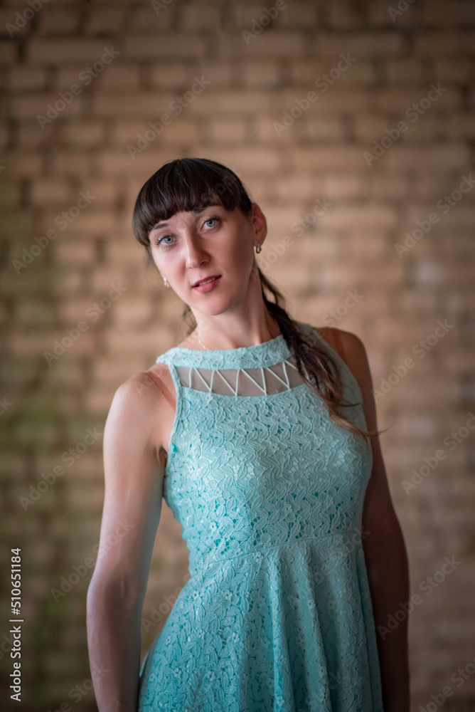Portrait of a young beautiful dark-haired girl in a dress against a brick wall. There is artistic blur. Portrait of a young beautiful dark-haired girl in a dress against a brick wall. There is artistic blur.