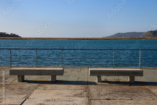 Two stone benches in front of a estuary near the sea