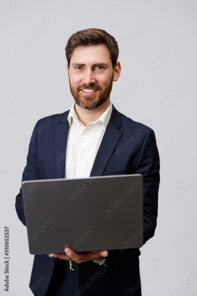 Cheerful man in suit holding laptop over grey background Cheerful man in suit holding laptop over grey background