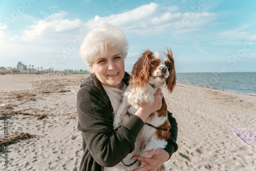 Joyful elderly lady with her pet at the seaside