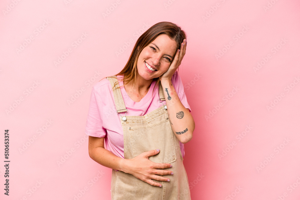 Young caucasian pregnant woman isolated on white background laughs happily and has fun keeping hands on stomach. Young caucasian pregnant woman isolated on white background laughs happily and has fun keeping hands on stomach.