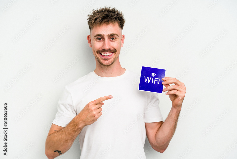 Young caucasian man holding wifi placard isolated on white background smiling and pointing aside, showing something at blank space. Young caucasian man holding wifi placard isolated on white background smiling and pointing aside, showing something at blank space.