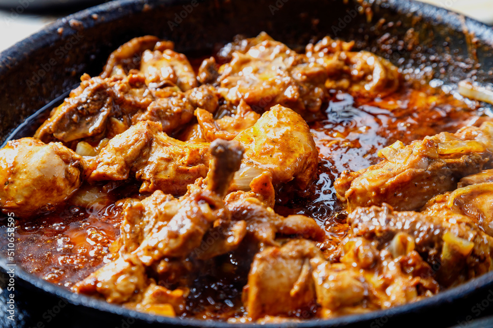 Fried chicken in spices and sauce is hot in a frying pan. Fried chicken in spices and sauce is hot in a frying pan.