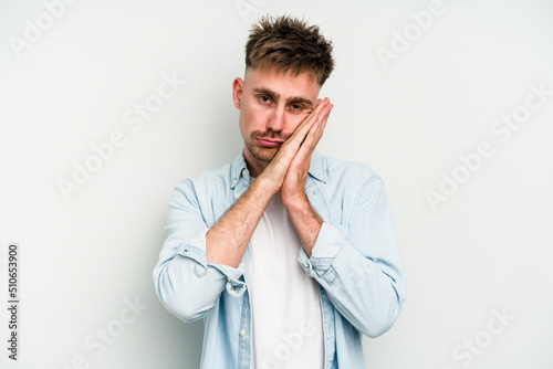 Young caucasian man isolated on white background yawning showing a tired gesture covering mouth with hand.