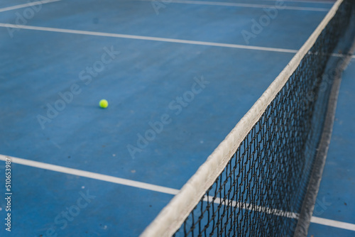 Tennis net and ball across a blue court.