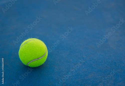 Close up of yellow tennis ball on a blue hard court.