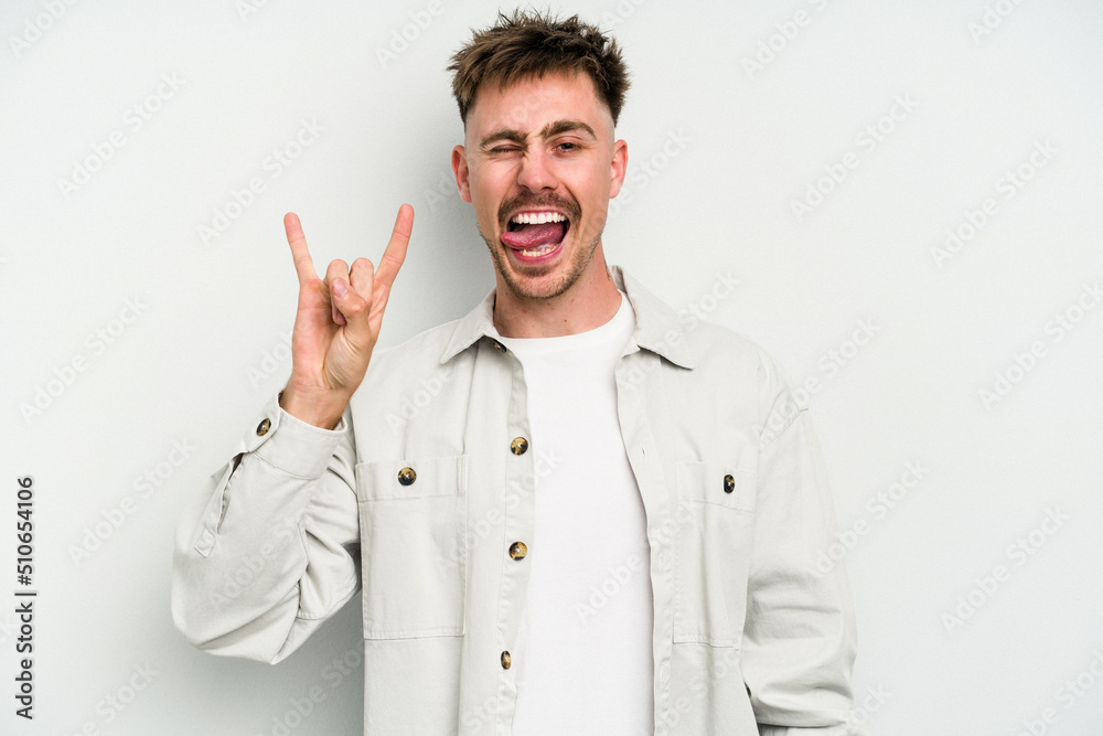 Young caucasian man isolated on white background showing rock gesture with fingers Young caucasian man isolated on white background showing rock gesture with fingers