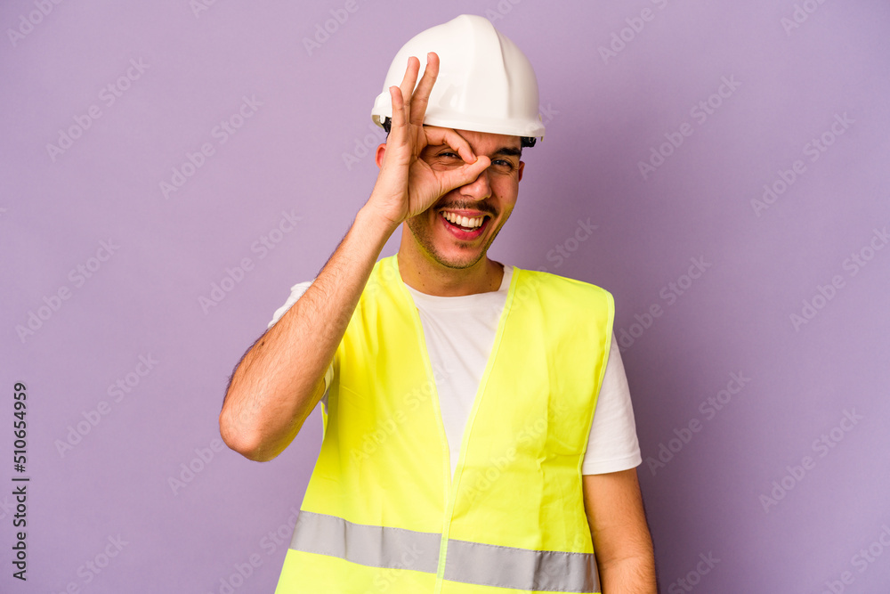 Young hispanic worker man isolated on purple background excited keeping ok gesture on eye.