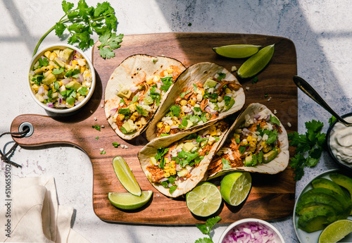 Overhead of soft tacos with chicken, corn, avocado and lime. photo