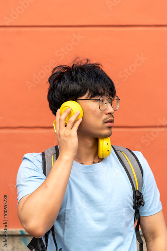 asian man listening to music from his headphones photo