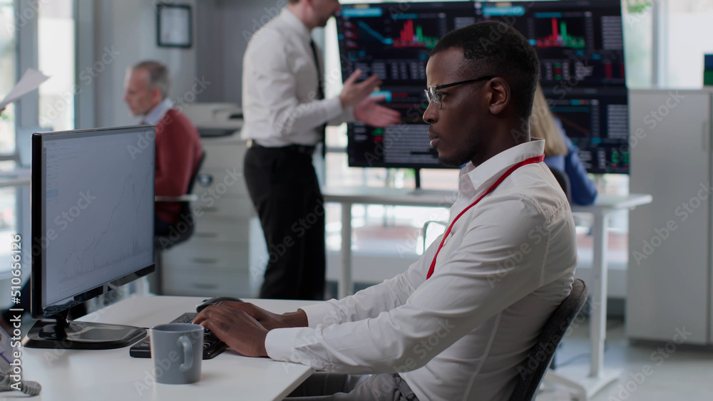 African-American financial specialist with cup of coffee sit down at workplace and type on computer