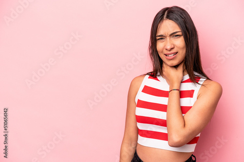 Young hispanic woman isolated on pink background touching back of head  thinking and making a choice.