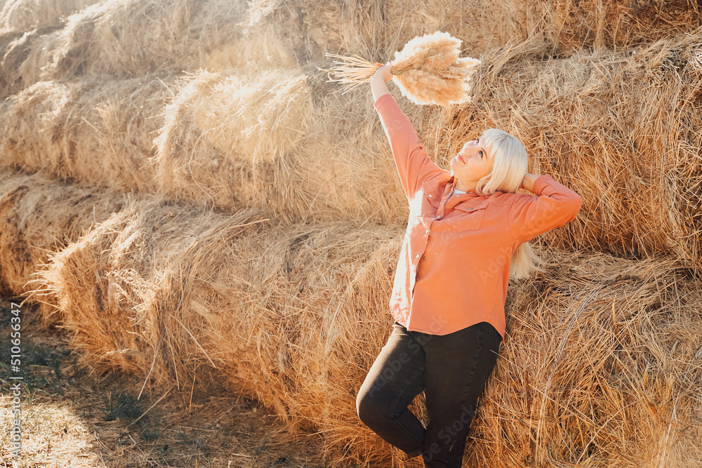 Autumn, the girl enjoys nature in the field and hayloft. Beauty girl outdoors raising her hands in the sun. Free happy woman Autumn, the girl enjoys nature in the field and hayloft. Beauty girl outdoors raising her hands in the sun. Free happy woman