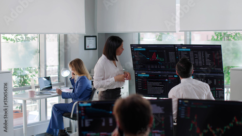 Financial manager discuss graphs on multiple screens with analyst in modern finance company
