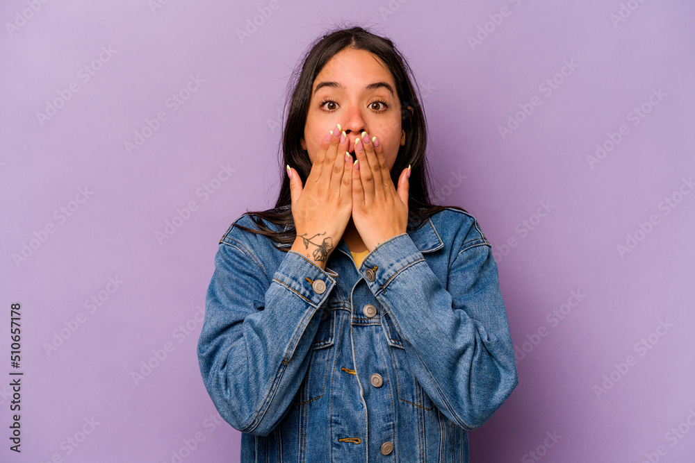 Young hispanic woman isolated on purple background shocked, covering mouth with hands, anxious to discover something new. Young hispanic woman isolated on purple background shocked, covering mouth with hands, anxious to discover something new.