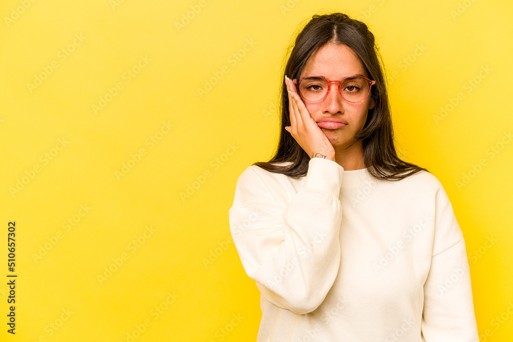 Young hispanic woman isolated on yellow background who feels sad and pensive, looking at copy space.