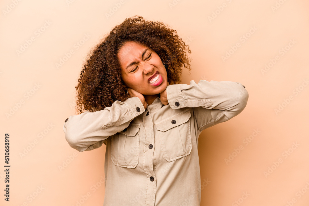 Young African American woman isolated on beige background suffering neck pain due to sedentary lifestyle. Young African American woman isolated on beige background suffering neck pain due to sedentary lifestyle.