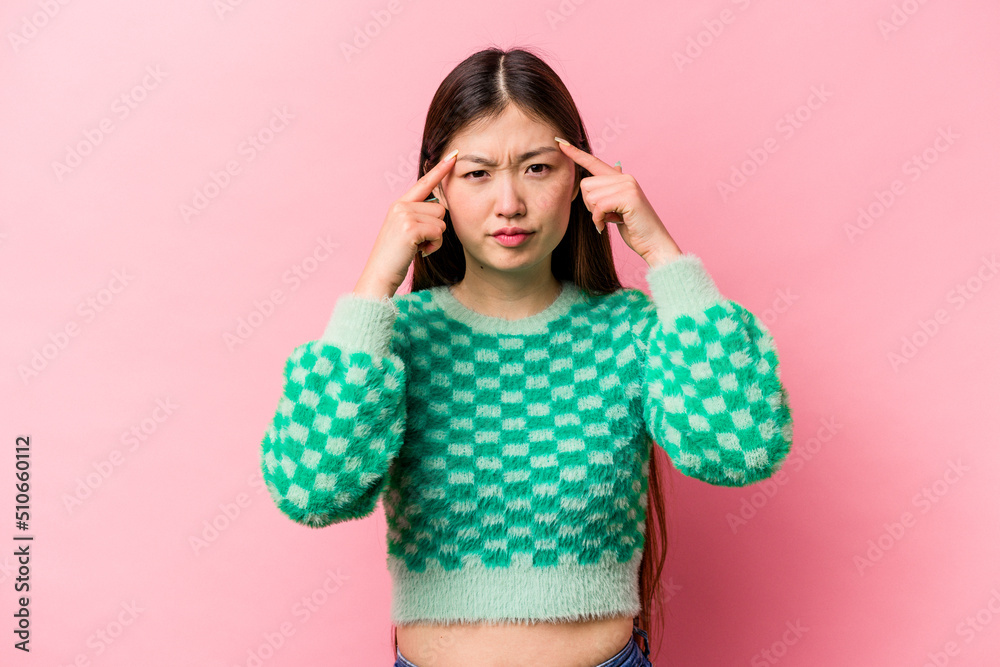 Young Chinese woman isolated on pink background focused on a task, keeping forefingers pointing head. Young Chinese woman isolated on pink background focused on a task, keeping forefingers pointing head.