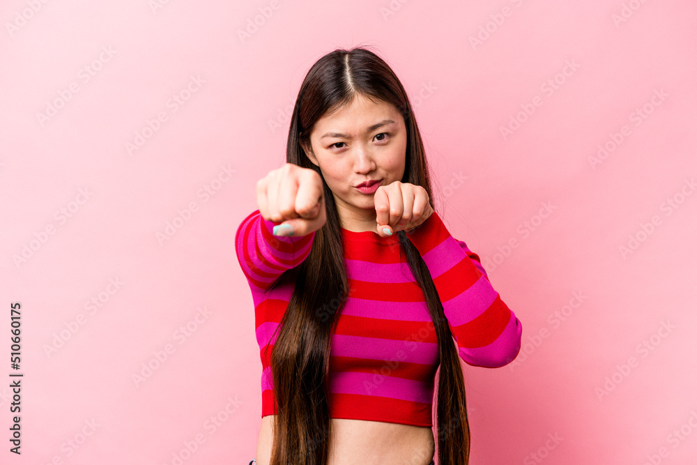 Young Chinese woman isolated on pink background throwing a punch, anger, fighting due to an argument, boxing. Young Chinese woman isolated on pink background throwing a punch, anger, fighting due to an argument, boxing.